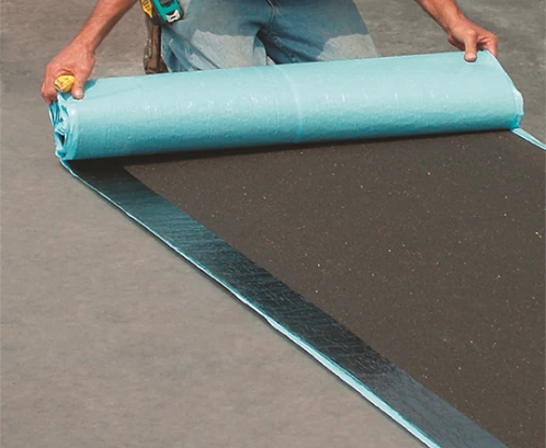 A bill West crew member rolling out material on a flat roofing job in Kansas City