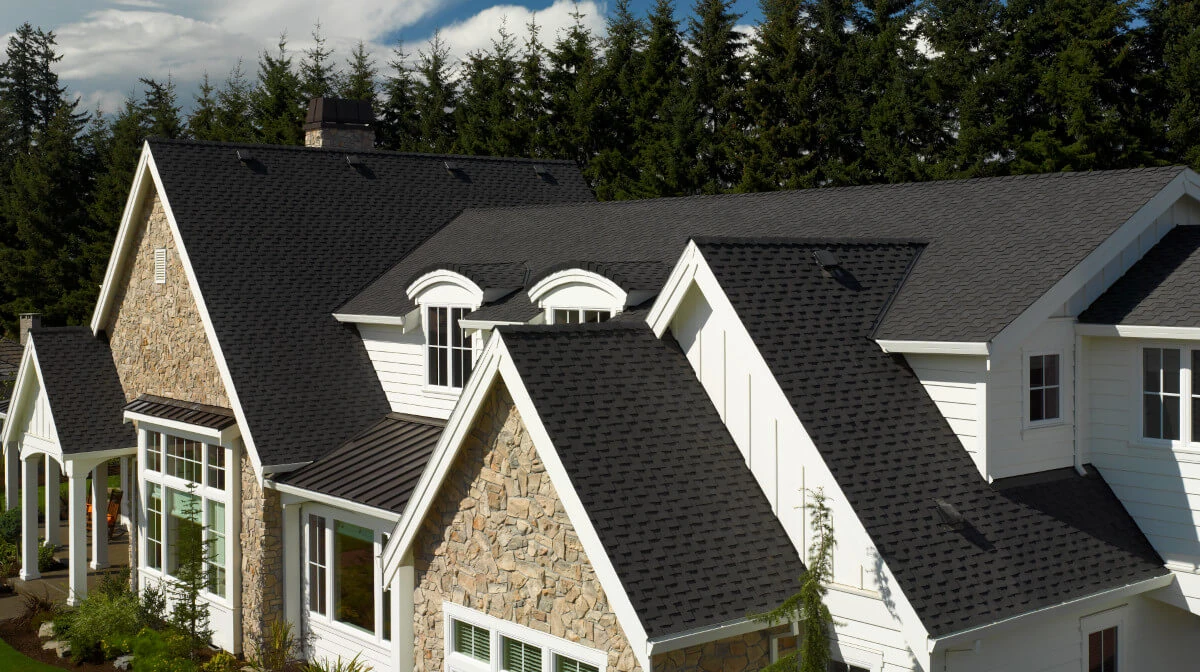 A beautiful rock faced home with a new black shingle roof installed by Bill West Roofing.