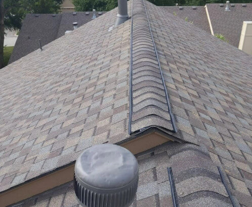 Aerial view of a home with new boot pipes, a new asphalt shingle roof and a new ridge vent installed by Bill West Roofing.