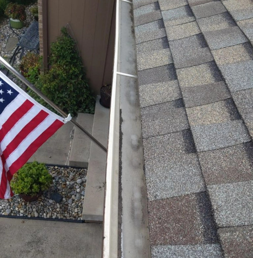 A new asphalt shingle roof on a home with an American flag hanging on the home.