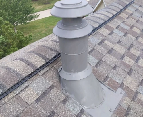 A pipe boot on an asphalt shingle roof with a ridge vent on the roof.