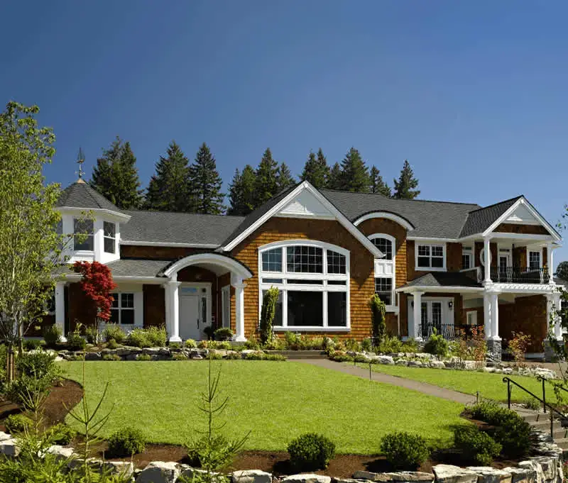 A beautiful Kansas City home with lush green grass and a new roof installed by Bill West Roofing.